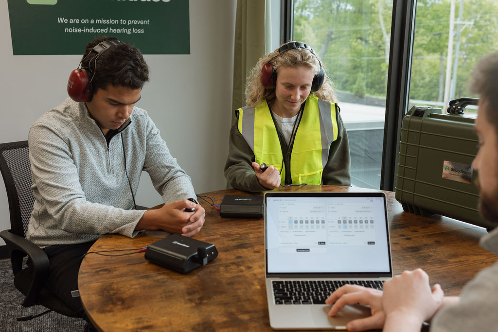 Two workers wearing audiometric headsets taking a Soundtrace hearing test on-site